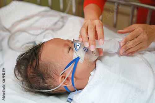 Baby has asthma and need nebulizations, Sick boy inhalation therapy by the mask of inhaler. Baby boy has a nasal congestion. Baby boy making inhalation with nebulizer. photo