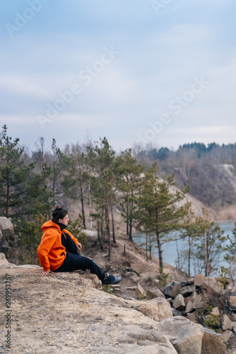A young man sitting on the edge of a cliff poses for the camera