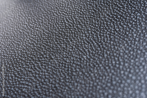 A macro or close-up shot of the visible and raised textured grain of a faux black leather with dramatic side lighting.