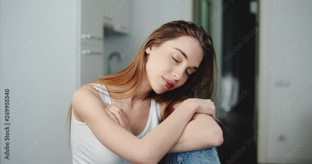 Close up portrait of pretty young woman dressed in white shirt sitting in the kitchen Close up portrait of pretty young woman dressed in white shirt sitting in the kitchen