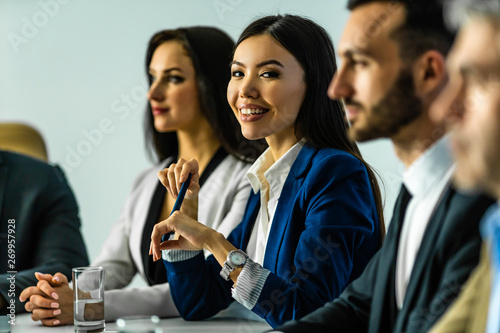 The woman sitting at the table near the colleagues