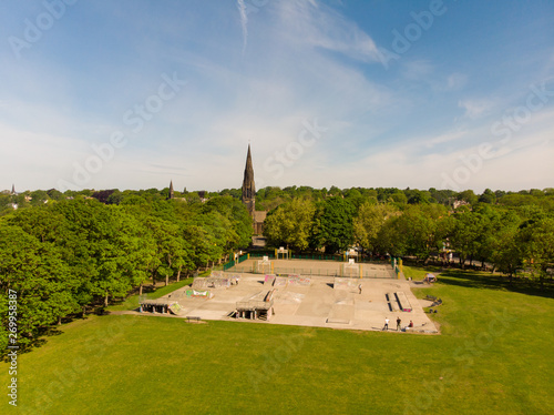 Aerial footage of the Leeds town of Headingley, the footage shows Terrence houses and homes and the town centre in the background with roads and traffic, taken on a beautiful sunny day.