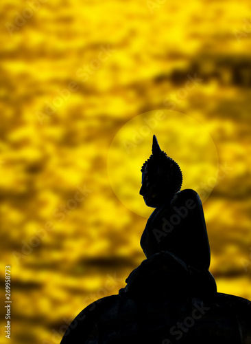 silhouette of buddha stature near river withgolden reflection background