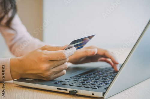 Close-up woman's hands holding a credit card and using computer keyboard for online shopping concept