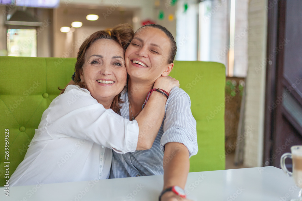 Happy mother spending time with adult daughter in cafe, family love caring time together concept Happy mother spending time with adult daughter in cafe, family love caring time together concept