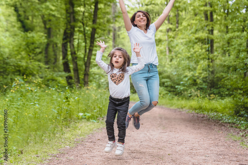 Young mom and little girl jump together together.