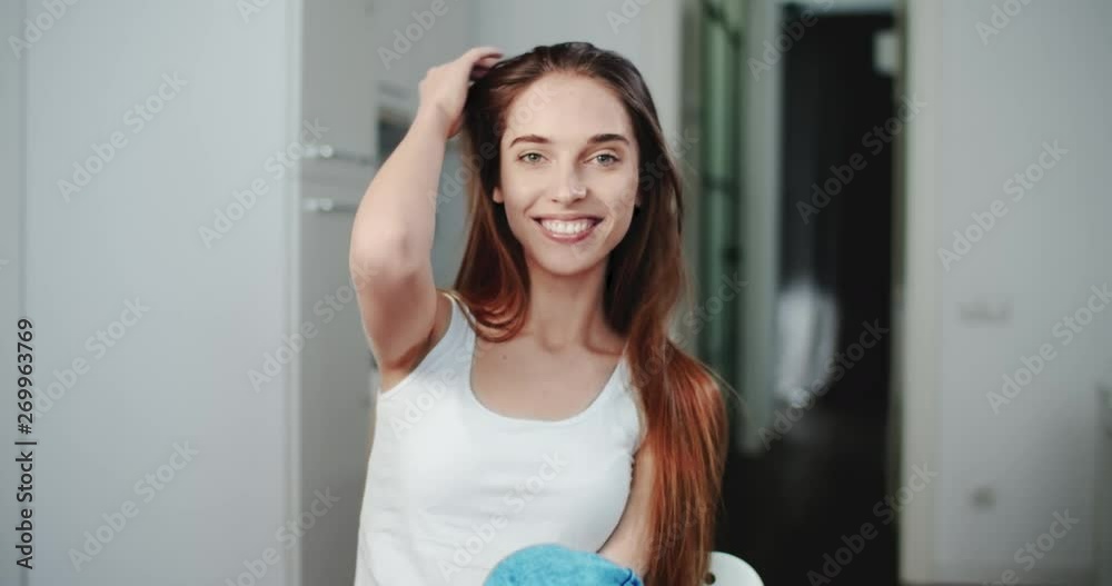 Portrait of pretty young smiling woman dressed in white shirt sitting in the kitchen Portrait of pretty young smiling woman dressed in white shirt sitting in the kitchen