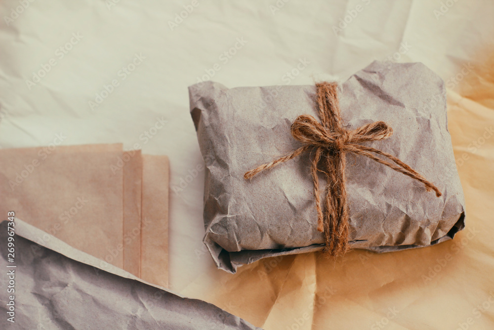 Soft parcel wrapped into old craft paper and tie. Crumpled background texture. Gift shop. Materials for transportation and shipping. Soft parcel wrapped into old craft paper and tie. Crumpled background texture. Gift shop. Materials for transportation and shipping.