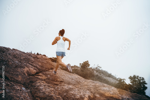 Young fitness woman running up to the seaside mountain top