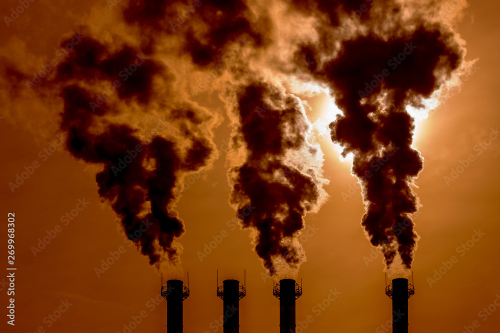 Black caustic poisonous smoke curls out of the pipes in the sunset sky. Toxic fumes chimney piping smoke or steam poisoned air, environmental pollution, environmental problems