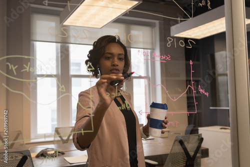 Businesswoman writing on glass wall photo