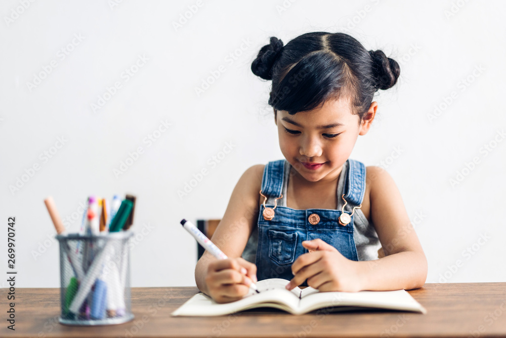 School kid little girl learning and writing in notebook with pencil making homework at home.Education concept School kid little girl learning and writing in notebook with pencil making homework at home.Education concept