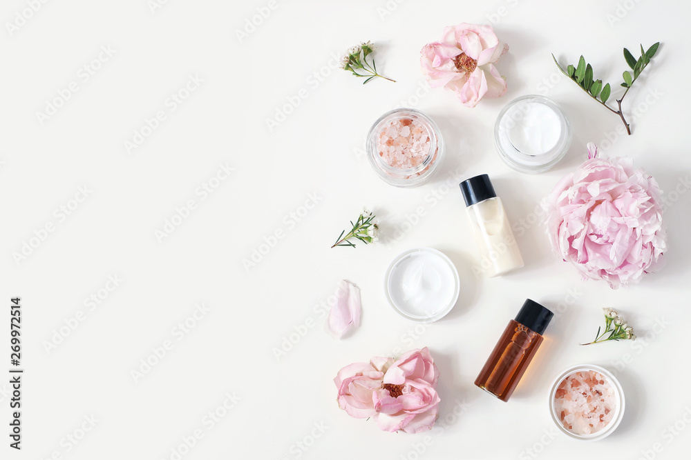 Plakat Styled beauty composition. Skin cream jar, tonicum bottle, roses, peony flower and Himalayan salt on white table background. Organic cosmetics, spa concept. Empty space, flat lay, top view.