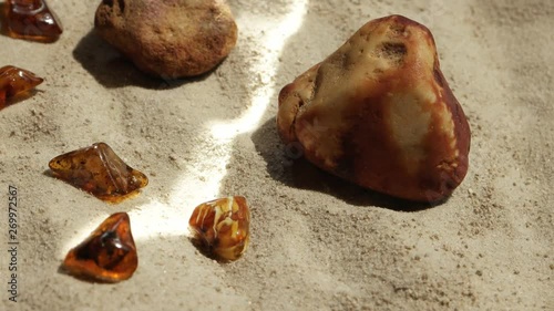 Sunbeam illumines stone and natural baltic amber against a background of sand photo