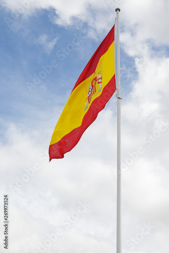 Flag of Spain against cloudy blue sky