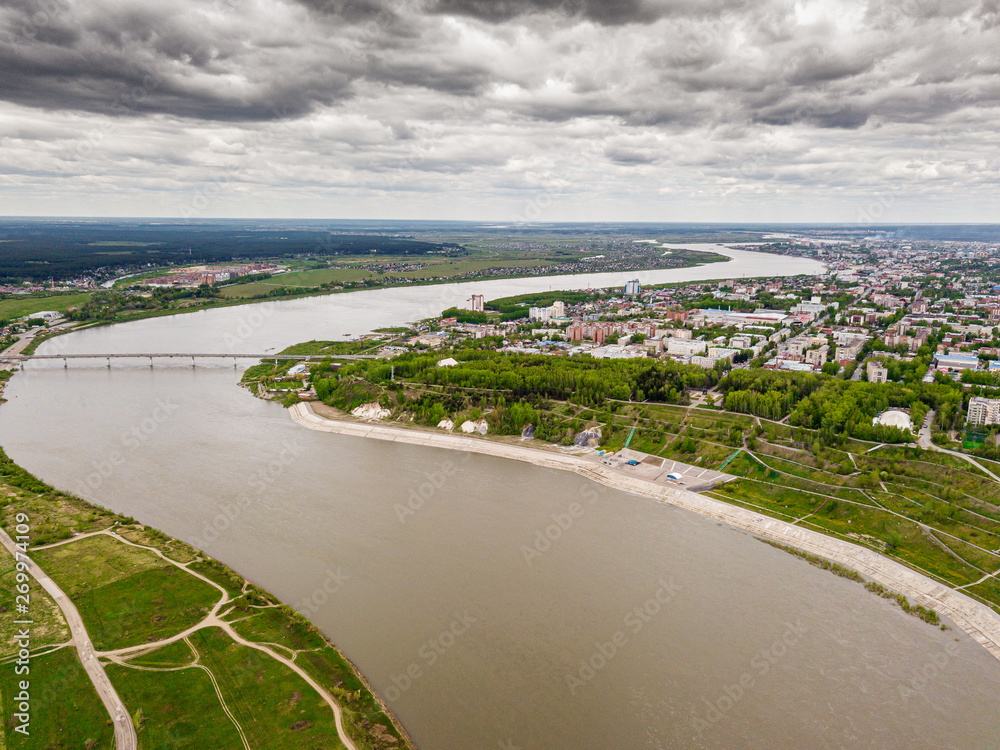 Tomsk cityscape and Tom river from aerial view. Modern city view. Dramatic landscape. Rainy and thunderstorm weather. Bridge through the river. Siberia, Russia