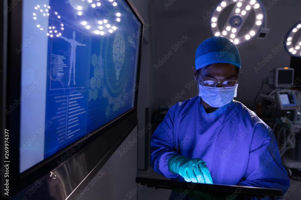 Male surgeon using digital tablet in operating room at hospital Male surgeon using digital tablet in operating room at hospital