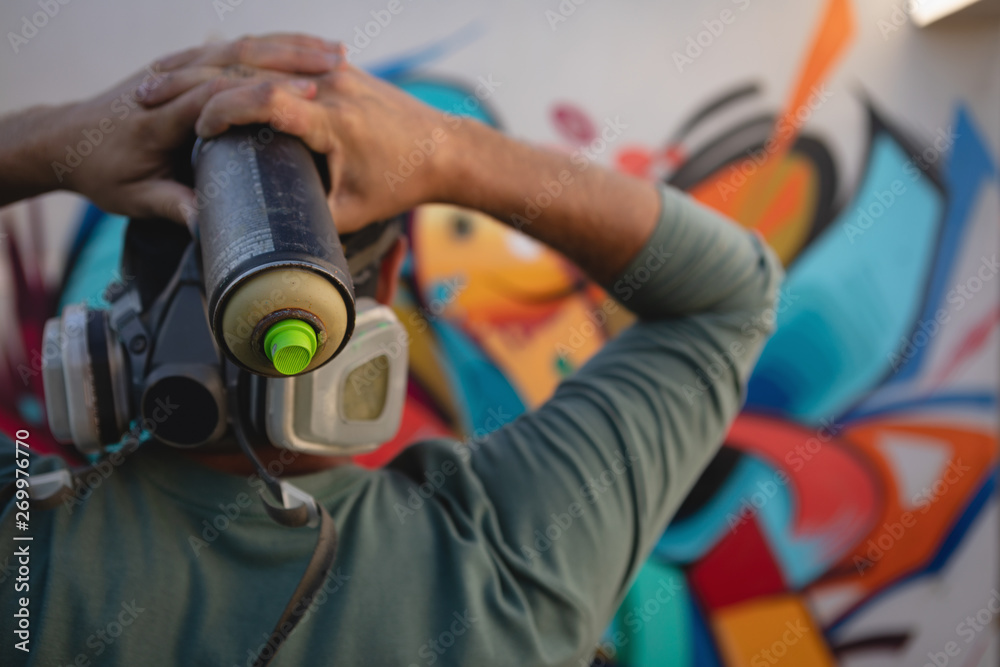Graffiti artist holding painting spray in font of the wall Stock Photo