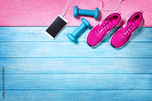 Fitness shoes over blue planks background. Sport shoes and accessories for sports activities on blue modern wooden floor, top view.