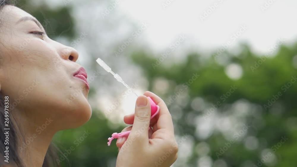 Close up face asian woman playing soap bubbles and having fun on outdoors at public park. Close up face asian woman playing soap bubbles and having fun on outdoors at public park.