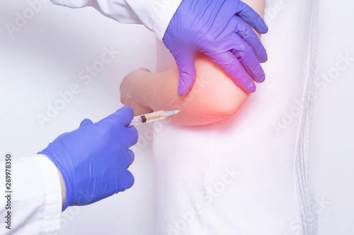 Doctor makes plasma-lifting injections into the girl s inflamed joint to relieve pain and inflammation, a modern anti-inflammatory method photo
