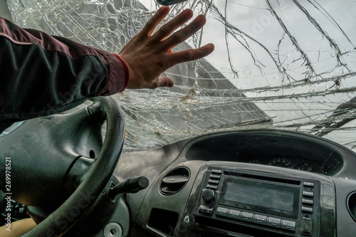 The man’s hand rests on the broken windshield of the car, photo from inside the car