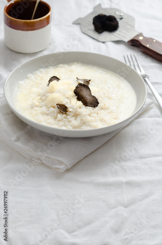 Risotto with black truffle and parmesan cheese  on white linen tablecloth, Copyspace.