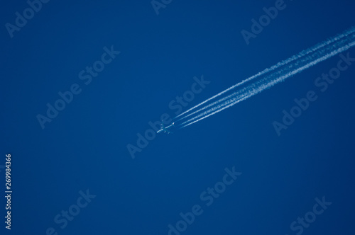 jet plane high in the blue sky with a contrail