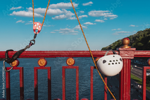Illegal banjee jumping. White helmet and rope hanging on the bridge railing against blue sky and river.