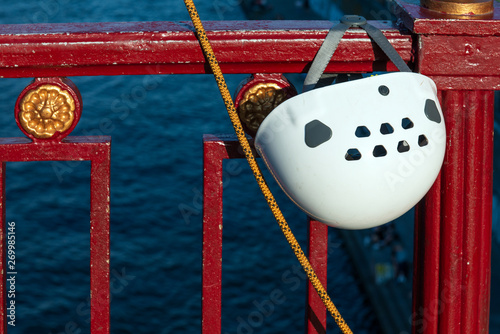 Illegal banjee jumping. White helmet and rope hanging on the bridge railing against river. Closeup. photo