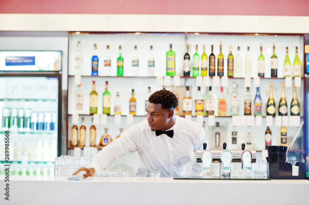 African american bartender wear on bow tie cleaning bar. African american bartender wear on bow tie cleaning bar.
