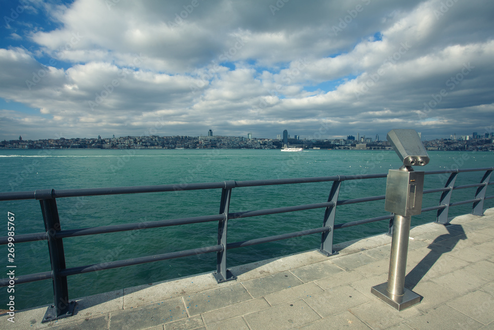 Travel concept. Tourist coin binocular at quay for promenade in Uskudar, the Bosphorus, Istanbul, Turkey. Sunny day. Blue cloudy sky. View to Galata Tower. Outdoor shot Travel concept. Tourist coin binocular at quay for promenade in Uskudar, the Bosphorus, Istanbul, Turkey. Sunny day. Blue cloudy sky. View to Galata Tower. Outdoor shot