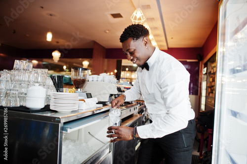 African american bartender at bar picks up ice. Alcoholic beverage preparation.