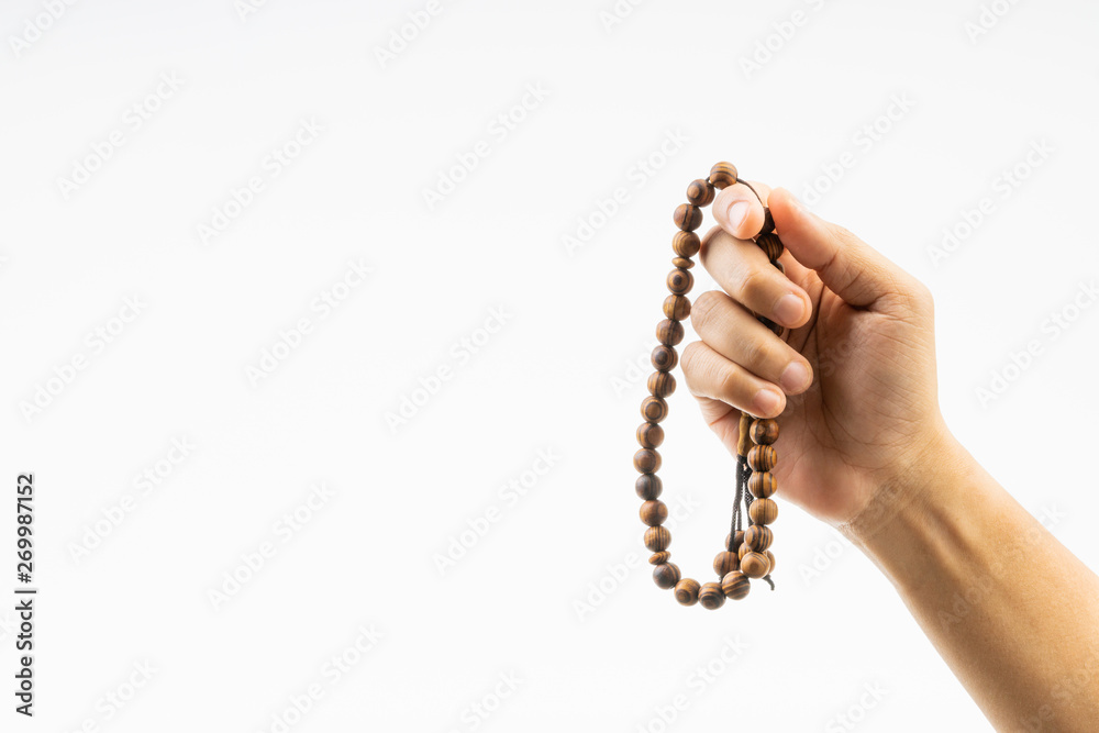 Hand holding a muslim rosary beads or Tasbih on white background. Copy space and selective focus Hand holding a muslim rosary beads or Tasbih on white background. Copy space and selective focus