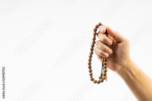 Hand holding a muslim rosary beads or Tasbih on white background. Copy space and selective focus