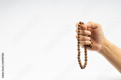 Hand holding a muslim rosary beads or Tasbih on white background. Copy space and selective focus photo