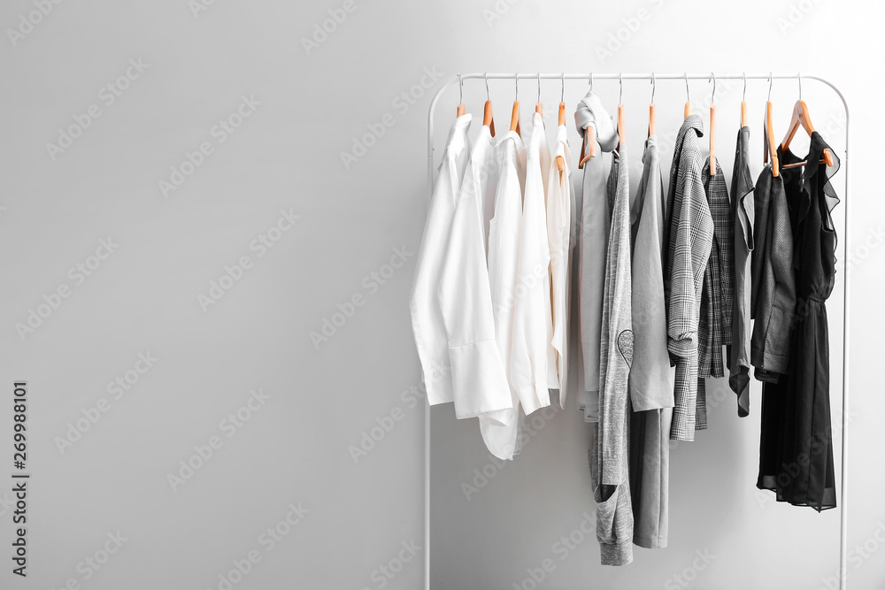 Fototapeta premium Stojak ze stylowymi ubraniami na jasnym tle