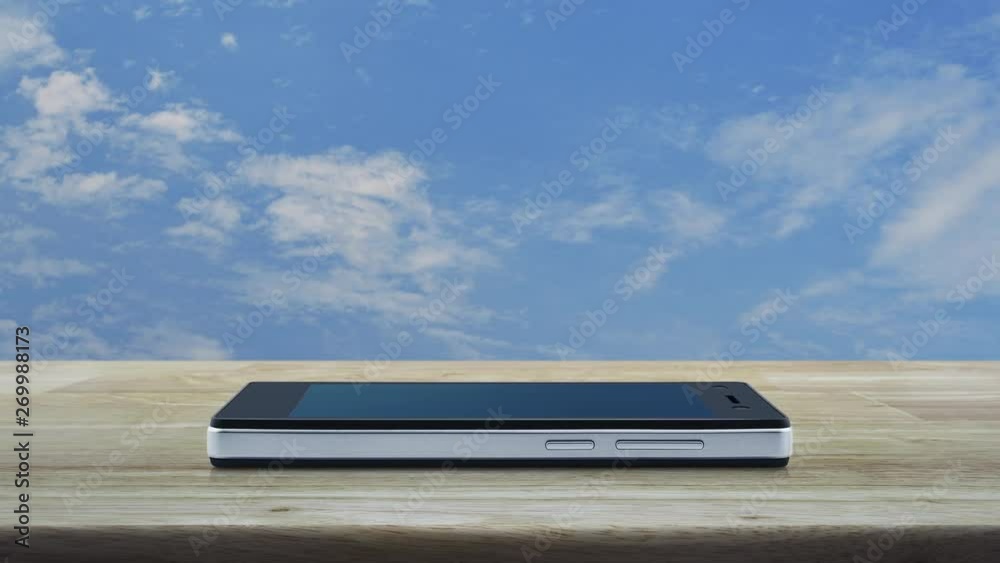 Bank flat icon on modern smart mobile phone screen on wooden table over blue sky with white clouds, Business banking online concept Bank flat icon on modern smart mobile phone screen on wooden table over blue sky with white clouds, Business banking online concept