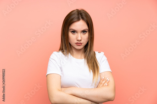 Teenager girl over isolated pink wall keeping arms crossed