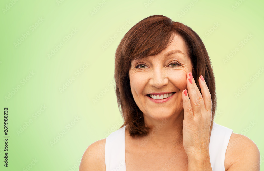 beauty, skin care and old people concept - portrait of smiling senior woman touching her face over lime green background beauty, skin care and old people concept - portrait of smiling senior woman touching her face over lime green background