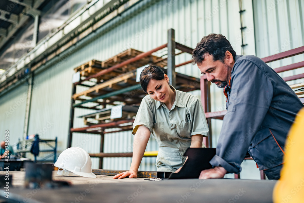 Male and female engineer discussing business at industrial hall. Male and female engineer discussing business at industrial hall.
