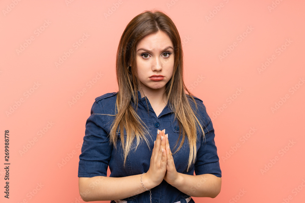 Teenager girl over isolated pink background keeps palm together. Person asks for something Teenager girl over isolated pink background keeps palm together. Person asks for something
