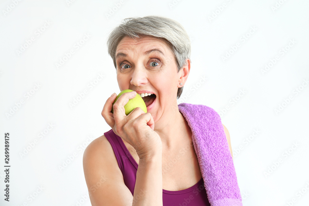 Sporty mature woman with towel and apple on white background Sporty mature woman with towel and apple on white background