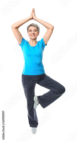 Mature woman practicing yoga on white background