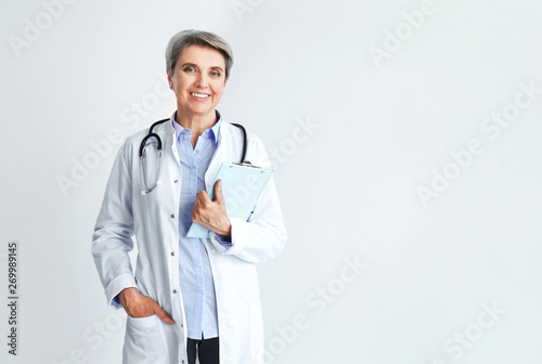Mature female doctor on light background photo