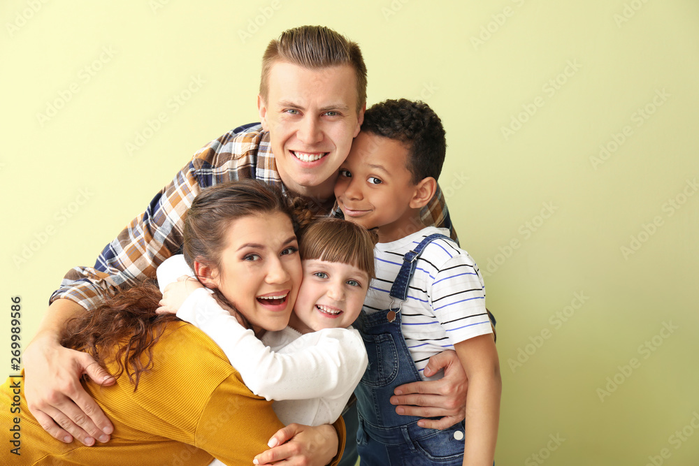 Happy couple with little adopted children on color background Happy couple with little adopted children on color background
