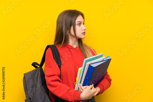 Teenager student girl over yellow background looking side