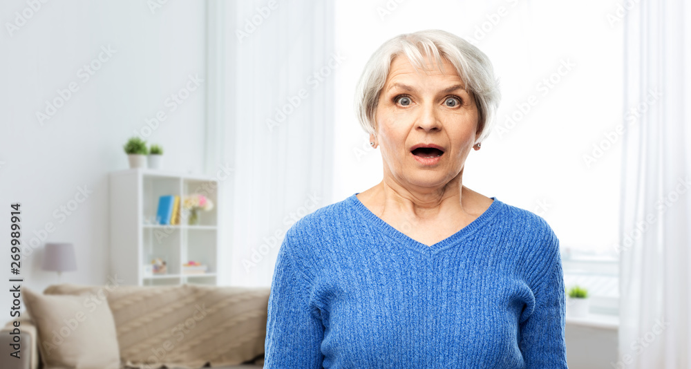 emotion, expression and old people concept - portrait of shocked senior woman in blue sweater with open mouth by hands over home living room background emotion, expression and old people concept - portrait of shocked senior woman in blue sweater with open mouth by hands over home living room background