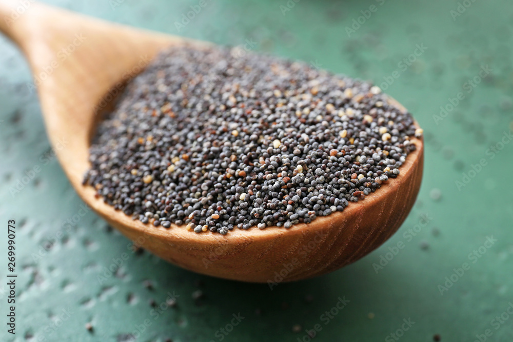 Spoon with poppy seeds on table, closeup Spoon with poppy seeds on table, closeup
