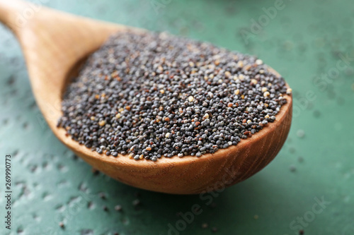 Spoon with poppy seeds on table, closeup